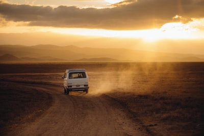 日落时行驶在沙漠田野上的白色车辆